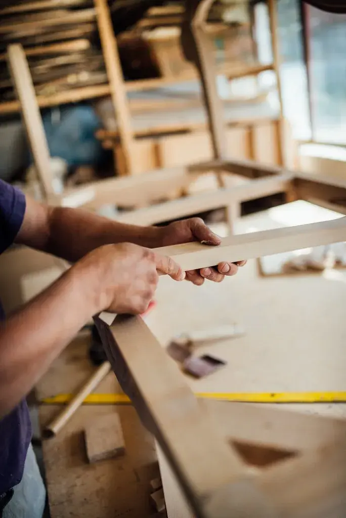 Twee vakmensen passen onderdelen van een houten meubelstuk in elkaar in een werkplaats